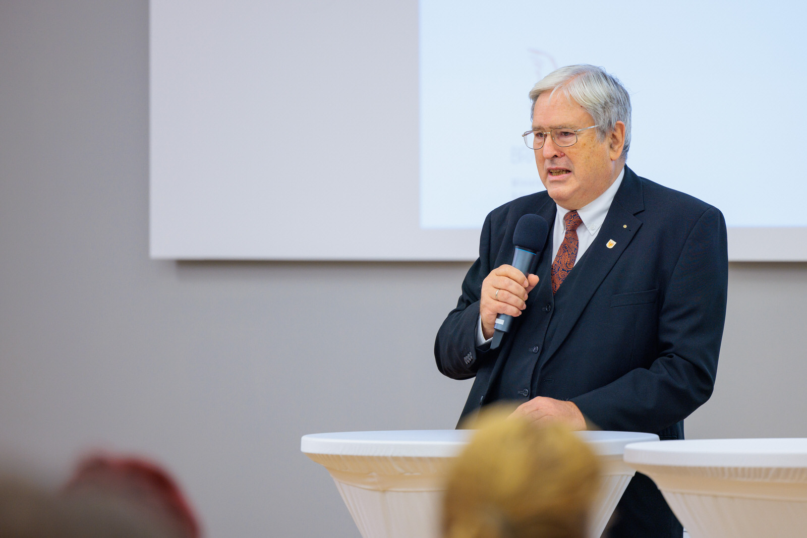 Bild: Prof. Dr.-Ing. Jörg Steinbach, Minister für Wirtschaft, Arbeit und Energie des Landes Brandenburg, steht an einem Stehtisch mit einem Mikro in der Hand