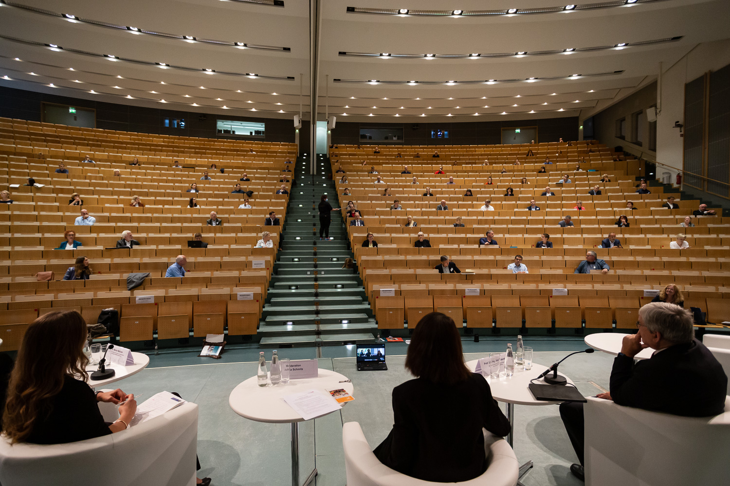 Bild: Das Bild zeigt die Podiumsdiskussion, aufgenommen von der Bühne aus, mit Blick auf das Publikum im Audimax.