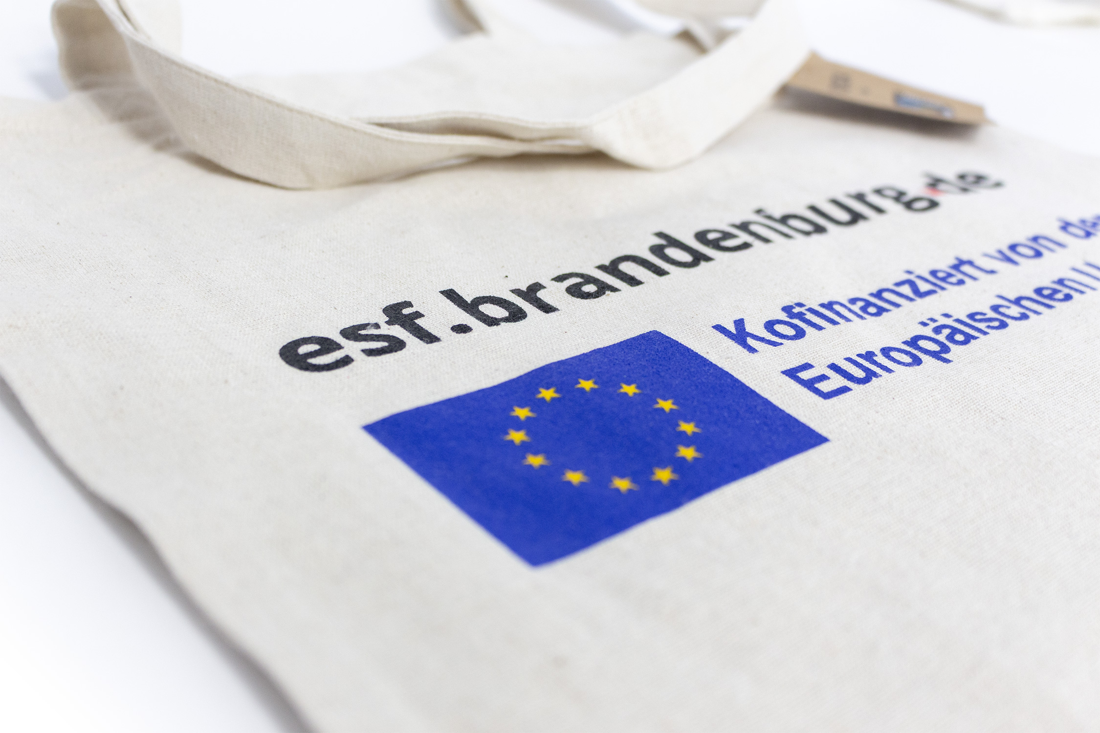 Bild vergrößern (Bild: Foto einer naturfarbenen einseitig bedruckten Baumwolltasche, 4-farbig bedruckt mit der URL esf.brandenburg.de und darunter das EU-Logo)