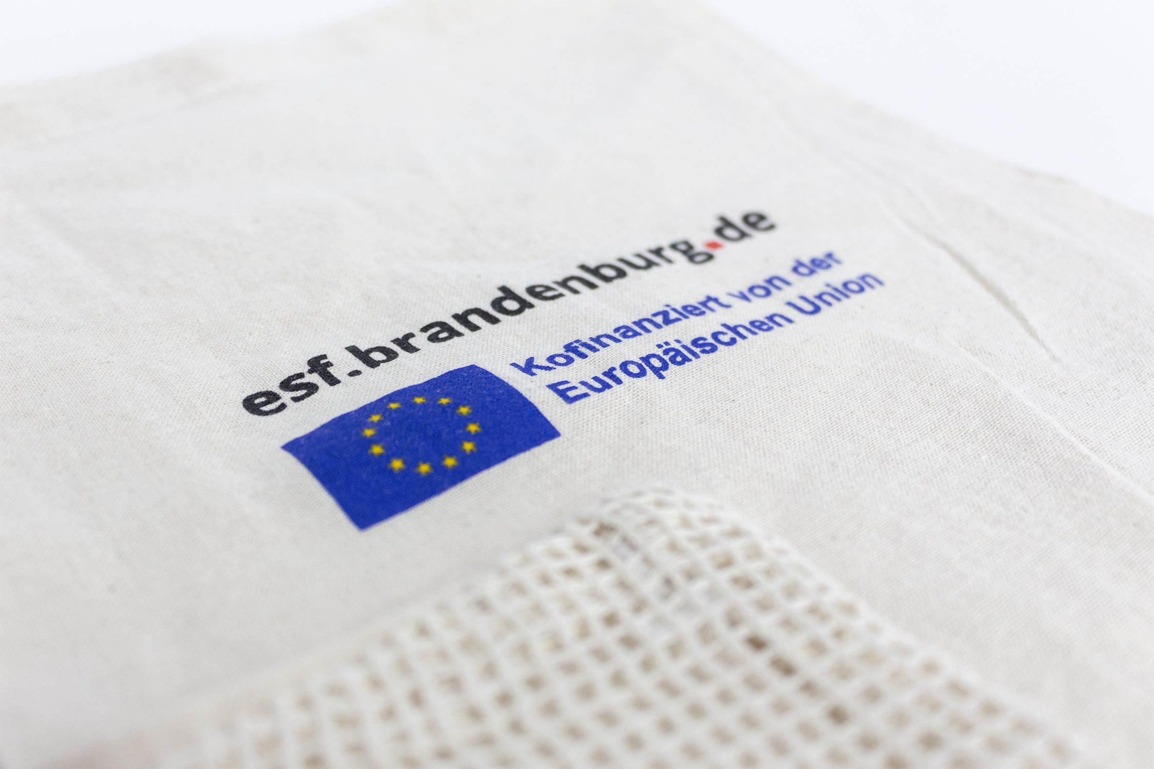 Bild vergrößern (Bild: Foto eines naturfarbenen einseitig bedruckten Einkaufsnetzes, 4-farbig bedruckt mit der URL esf.brandenburg.de und darunter das EU-Logo)