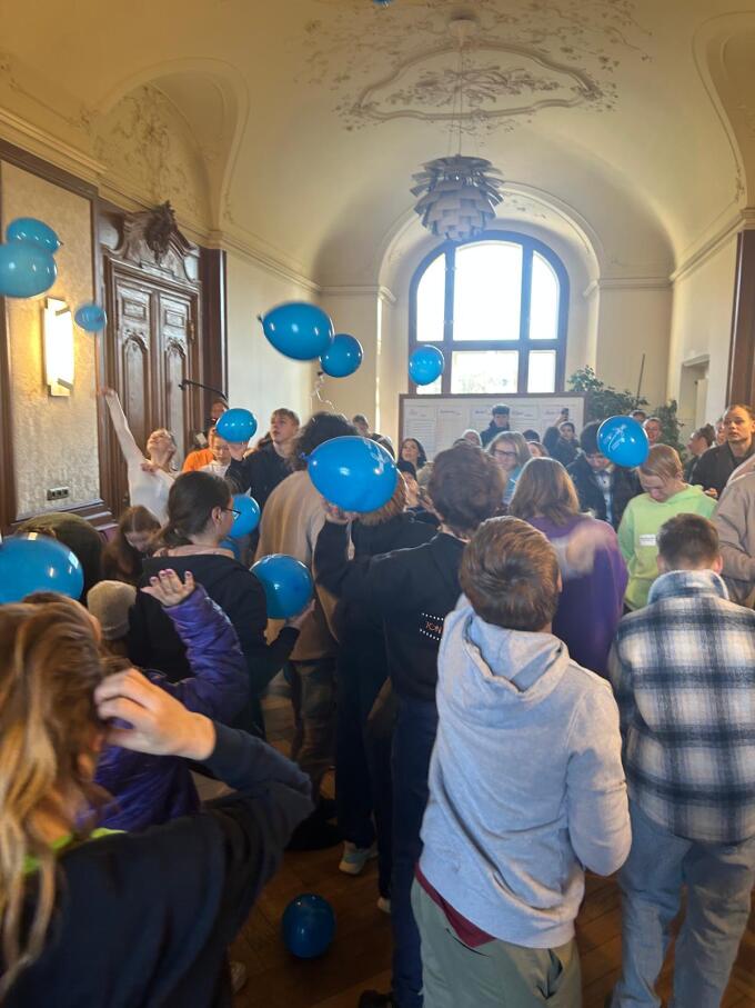 Viele junge Menschen die nach Luftballons greifen, die über ihnen schweben.