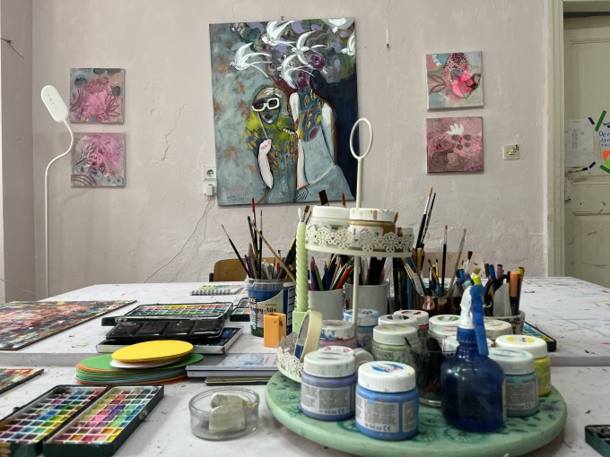 Verschiedene Kunstfarben und Materialien liegen auf einem Tisch.